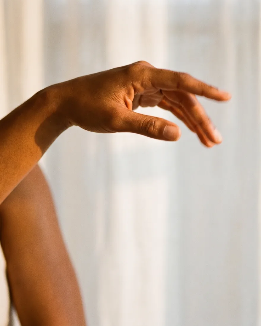 Una mano extendida en un gesto suave y abierto, con luz natural cálida
